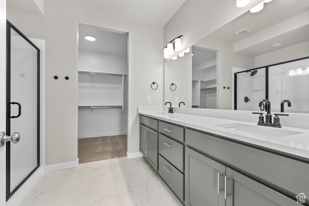 Bathroom featuring vanity with extensive cabinet space, tile flooring, double sink, and walk in shower