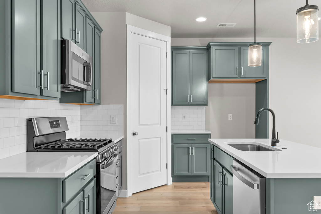 Kitchen featuring light hardwood / wood-style flooring, pendant lighting, stainless steel appliances, and sink