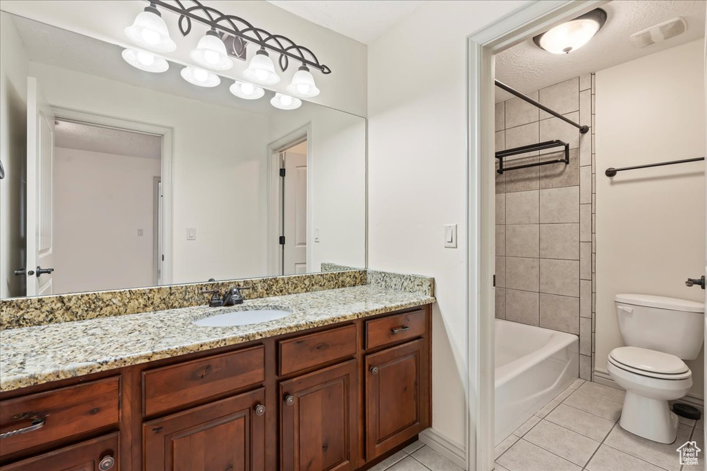 Full bathroom featuring tiled shower / bath combo, vanity, tile floors, and toilet
