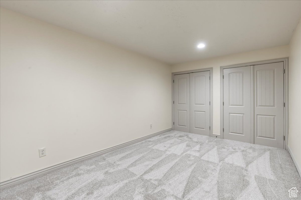Unfurnished bedroom with multiple closets and light colored carpet