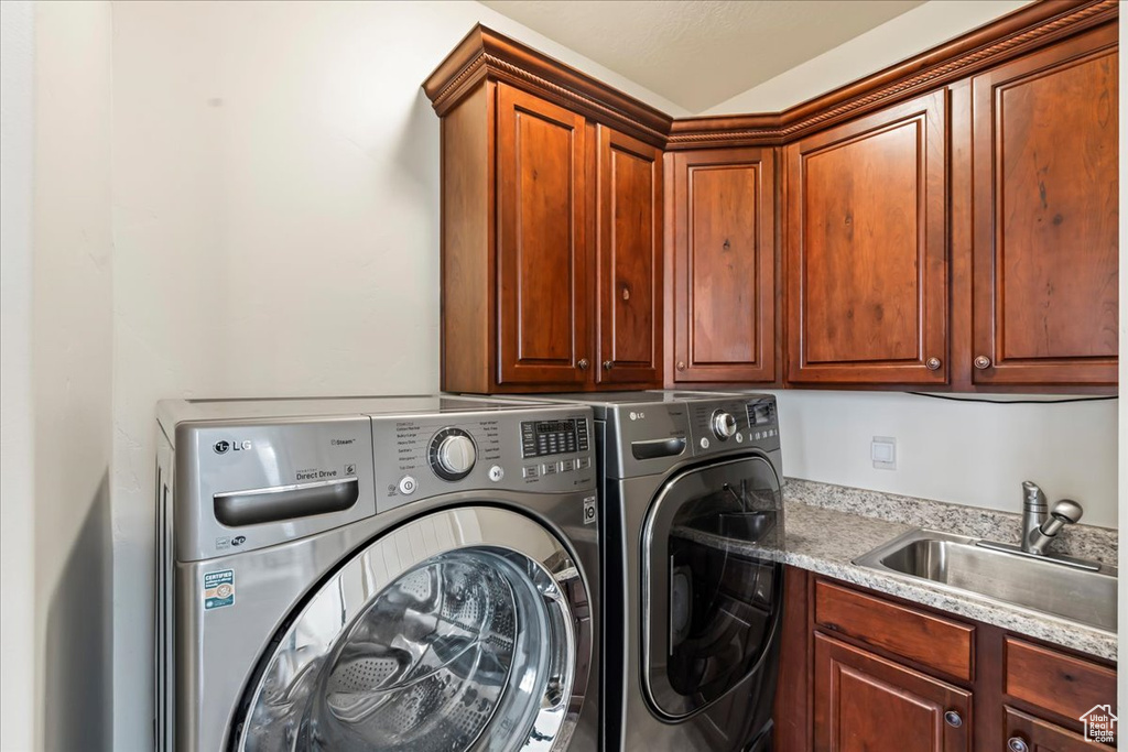 Laundry area with washing machine and clothes dryer, cabinets, and sink