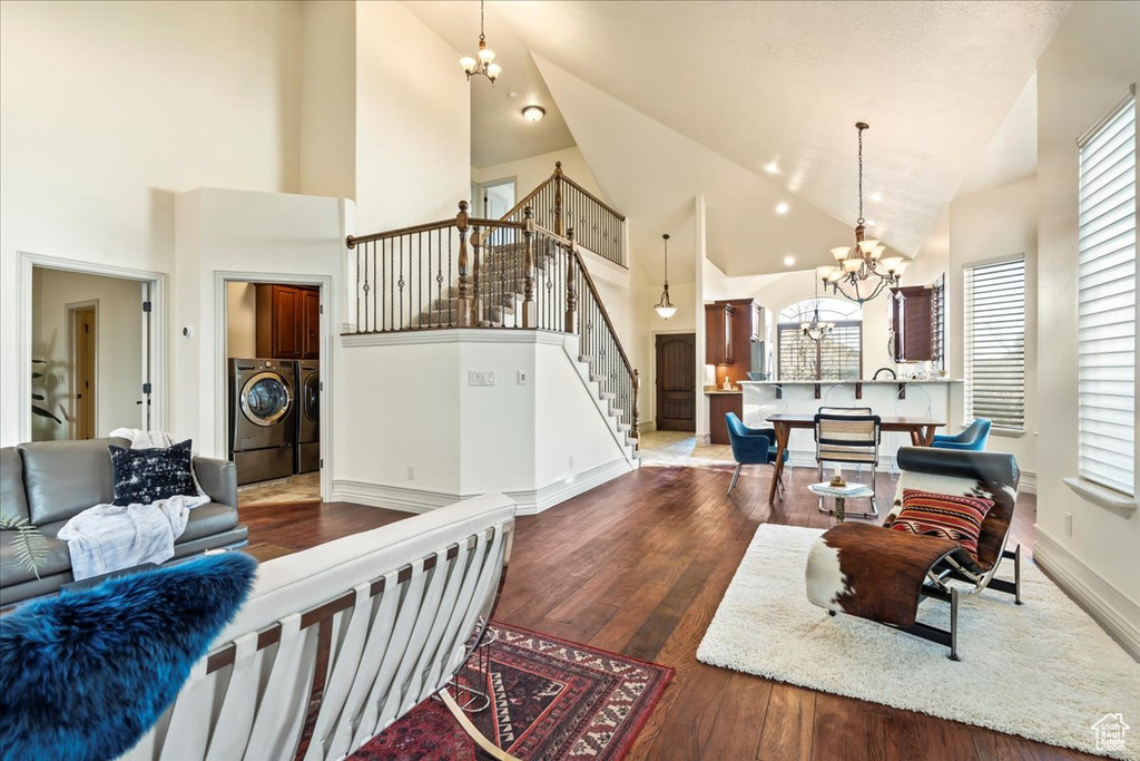 Living room with washing machine and clothes dryer, high vaulted ceiling, dark hardwood / wood-style floors, and a chandelier