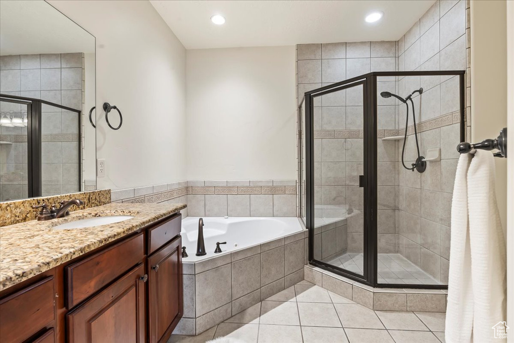 Bathroom featuring oversized vanity, shower with separate bathtub, and tile flooring