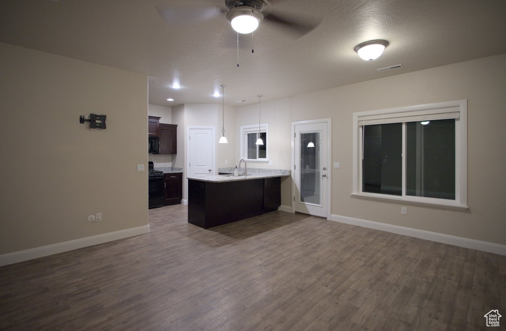 Kitchen with pendant lighting, kitchen peninsula, ceiling fan, and dark hardwood / wood-style floors