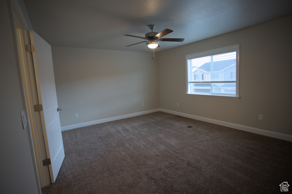 Unfurnished room with dark carpet and ceiling fan
