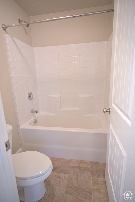 Bathroom with toilet, shower / washtub combination, and tile flooring