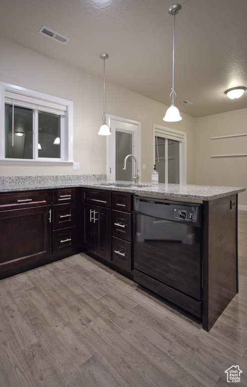 Kitchen featuring pendant lighting, black dishwasher, sink, and light wood-type flooring
