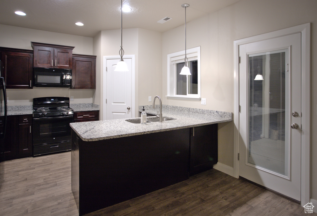 Kitchen featuring decorative light fixtures, dark hardwood / wood-style floors, black appliances, and sink