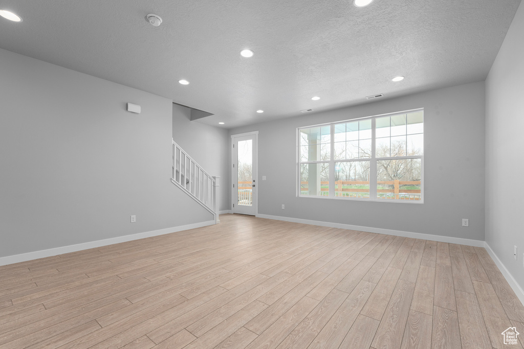 Spare room with a textured ceiling and light wood-type flooring