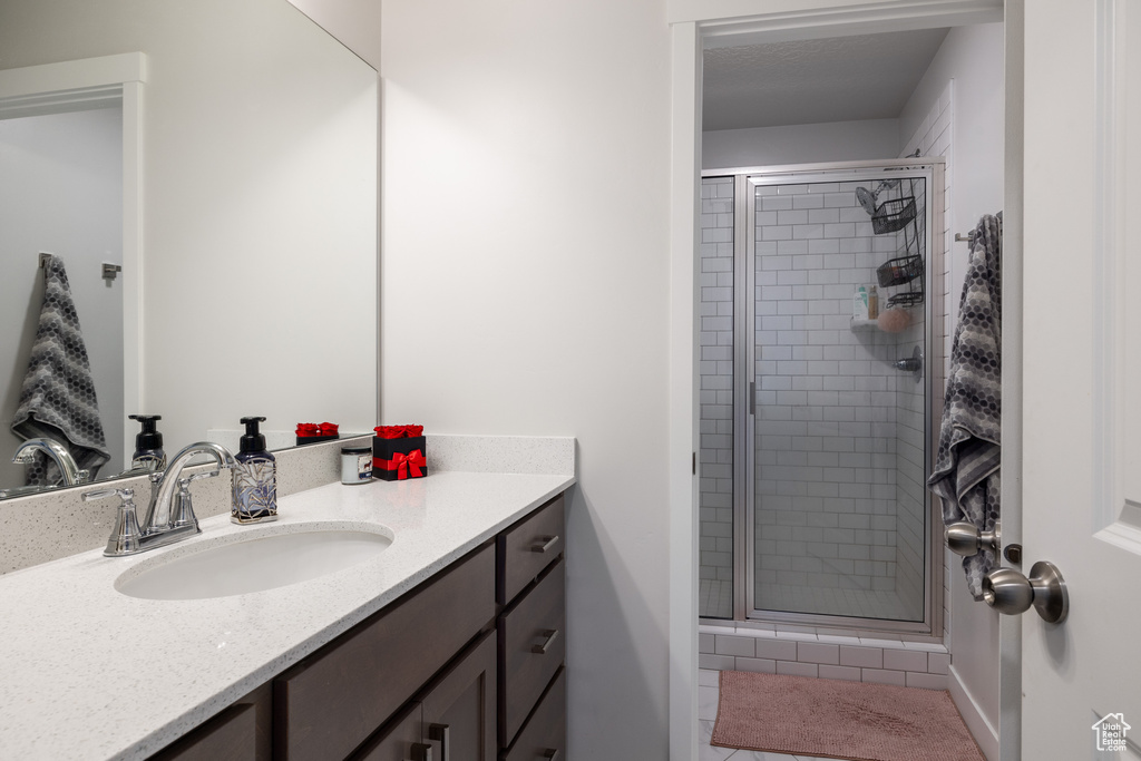 Bathroom featuring a shower with shower door and vanity