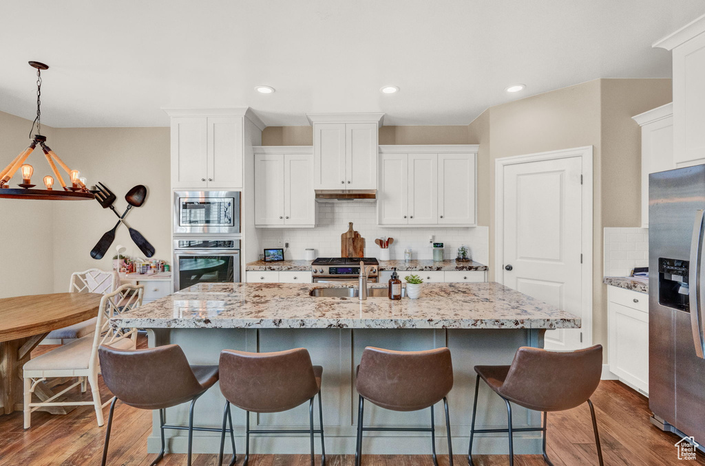 Kitchen featuring backsplash, pendant lighting, stainless steel appliances, and dark hardwood / wood-style flooring