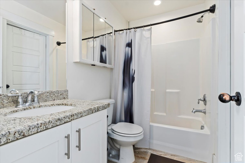 Full bathroom with tile floors, toilet, vanity, and shower / tub combo