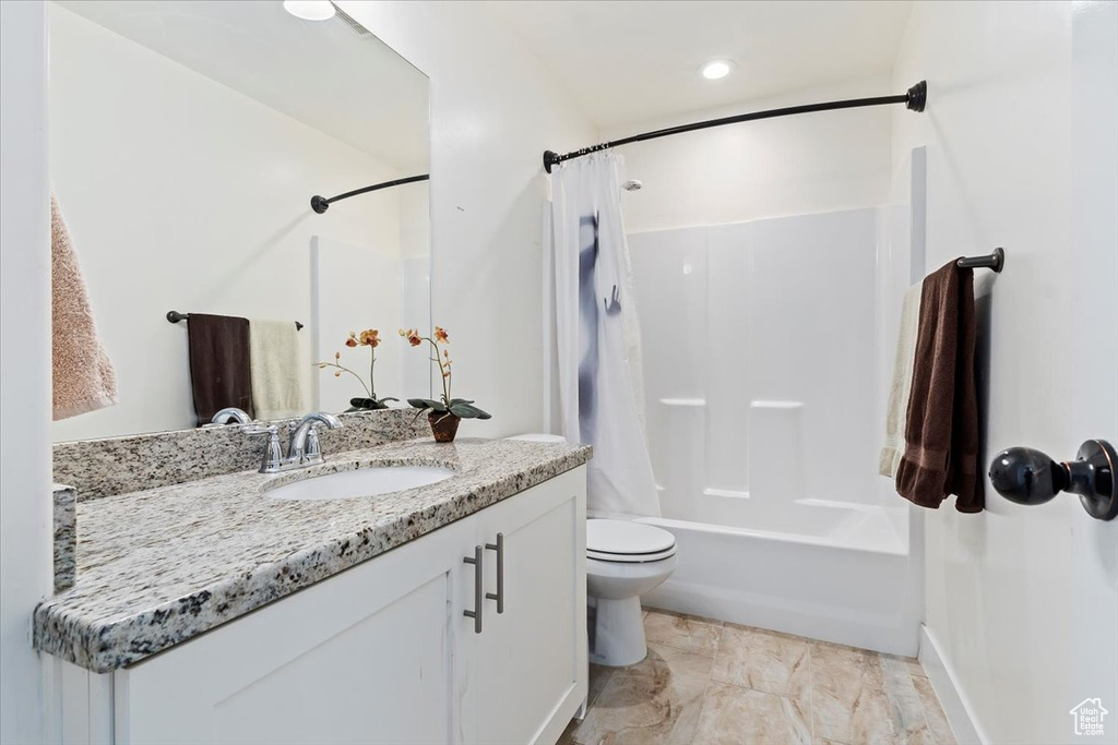 Full bathroom with toilet, vanity with extensive cabinet space, tile flooring, and shower / bathtub combination with curtain