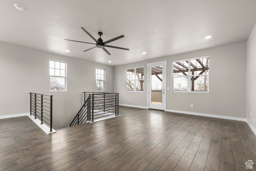 Spare room featuring dark hardwood / wood-style floors, ceiling fan, and a wealth of natural light