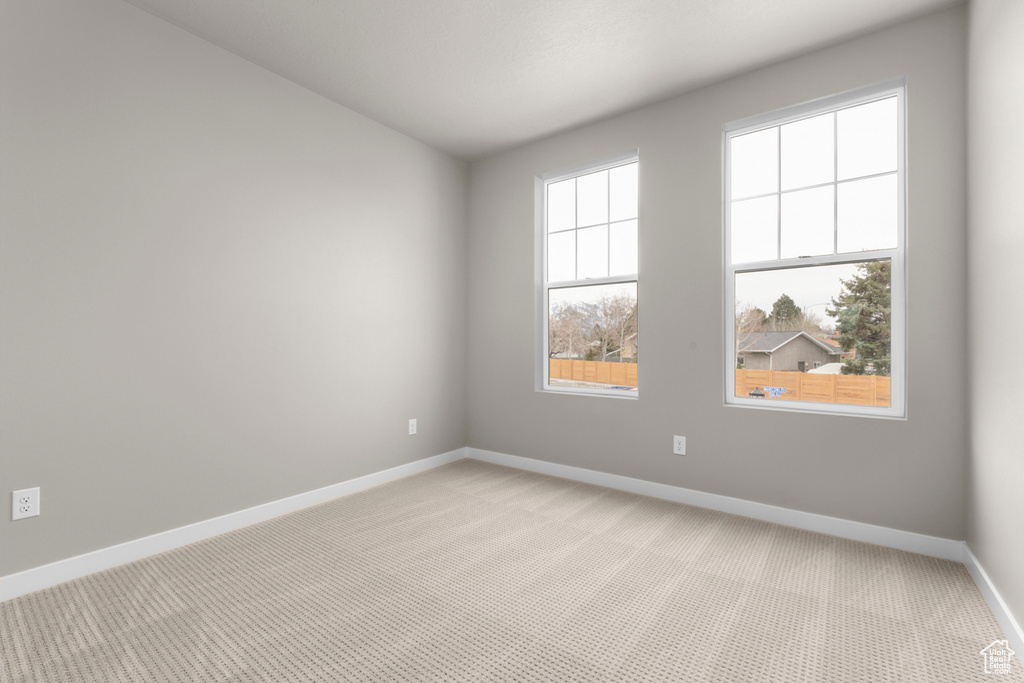 Empty room featuring a healthy amount of sunlight and light colored carpet
