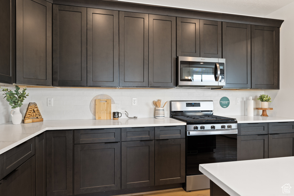 Kitchen with dark brown cabinetry, tasteful backsplash, and appliances with stainless steel finishes