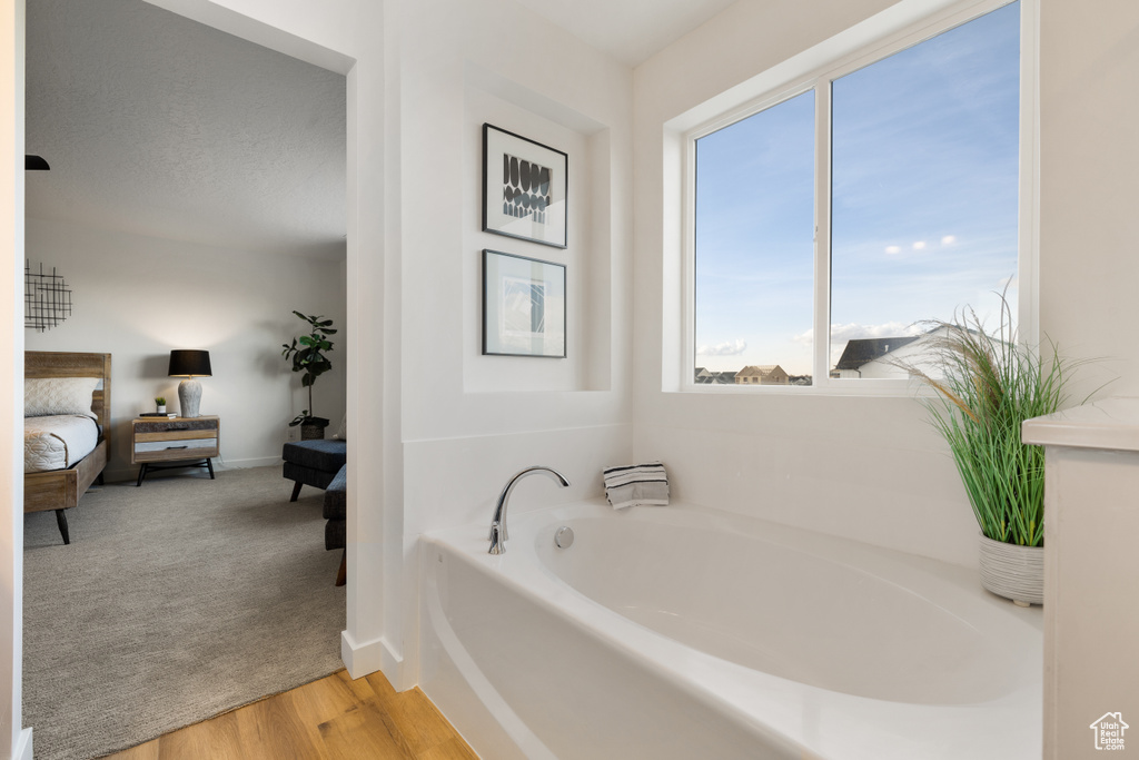 Bathroom with a bath to relax in, a healthy amount of sunlight, and hardwood / wood-style flooring