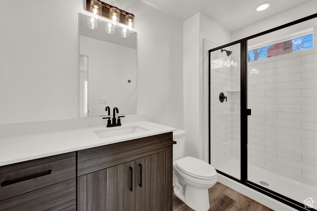 Bathroom featuring toilet, large vanity, hardwood / wood-style floors, and an enclosed shower