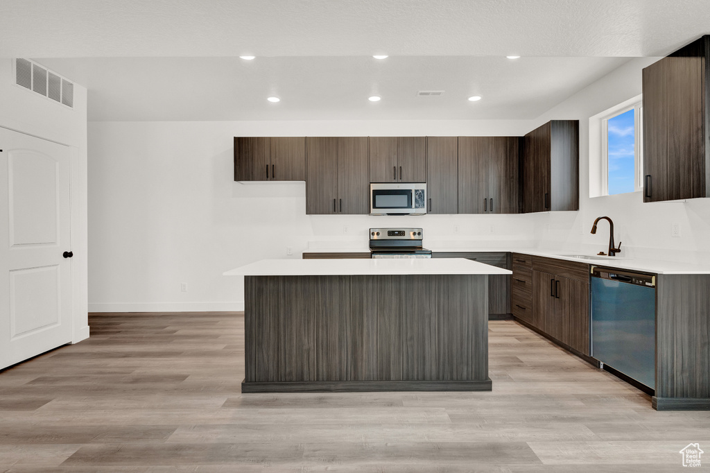 Kitchen featuring a kitchen island, stainless steel appliances, sink, and light hardwood / wood-style flooring