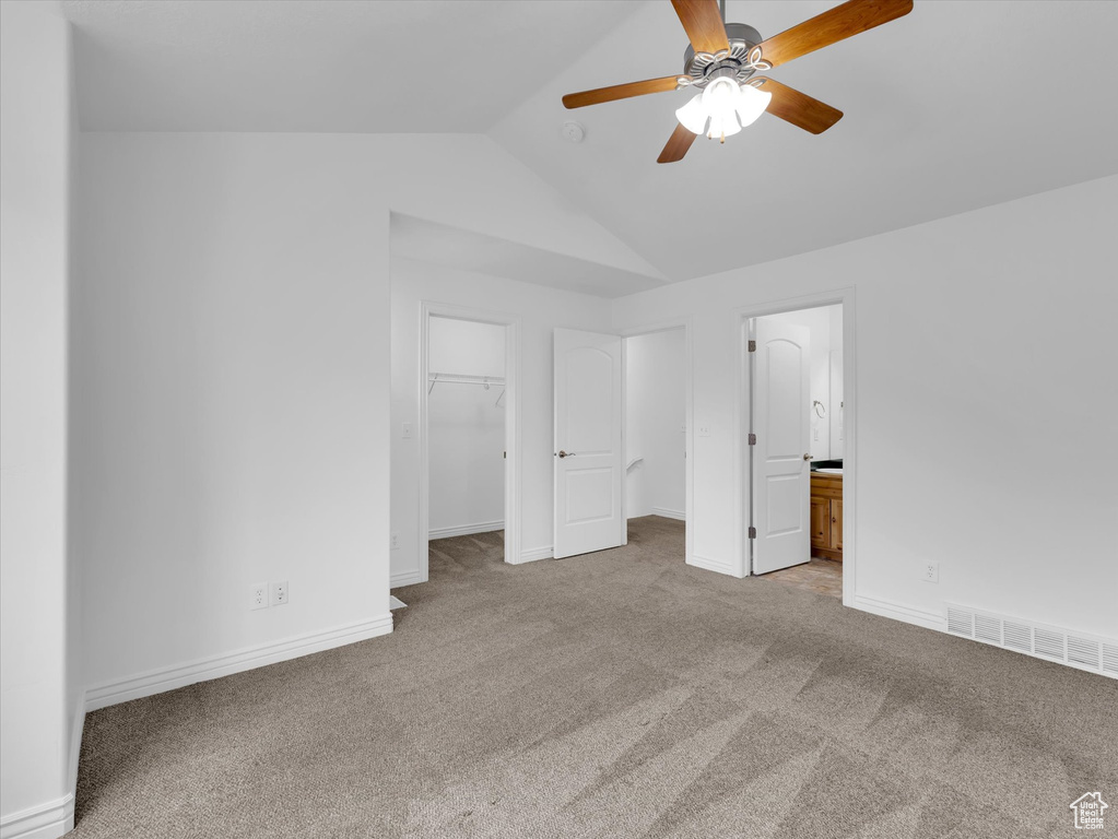 Unfurnished bedroom with connected bathroom, a walk in closet, ceiling fan, a closet, and light carpet