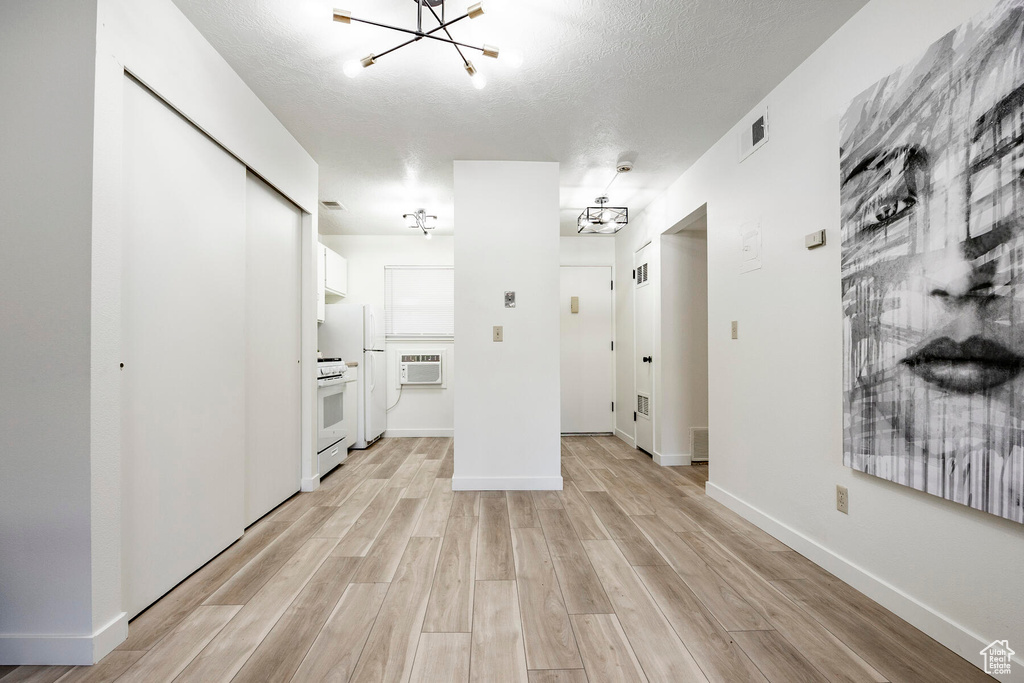 Interior space featuring an inviting chandelier, white cabinetry, white range, and light hardwood / wood-style floors
