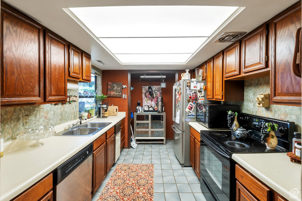Kitchen featuring tasteful backsplash, sink, light tile floors, and black appliances
