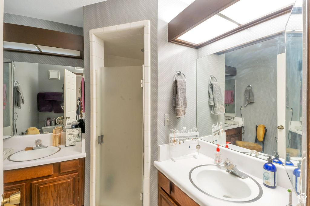 Bathroom featuring a shower with door and vanity with extensive cabinet space