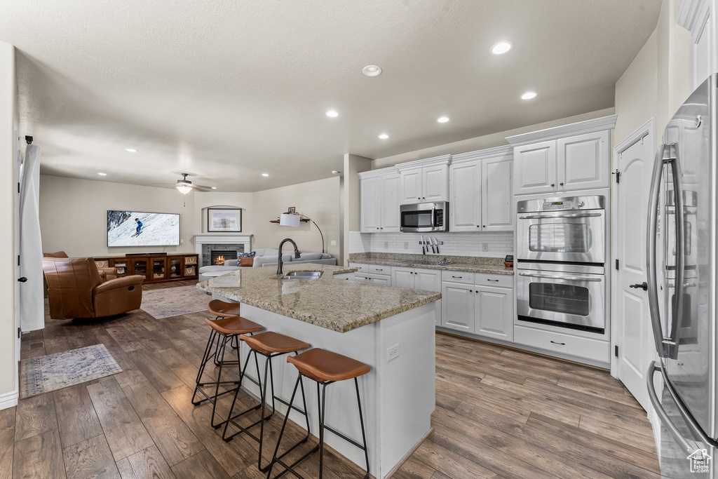 Kitchen featuring white cabinets, dark hardwood / wood-style flooring, ceiling fan, and appliances with stainless steel finishes
