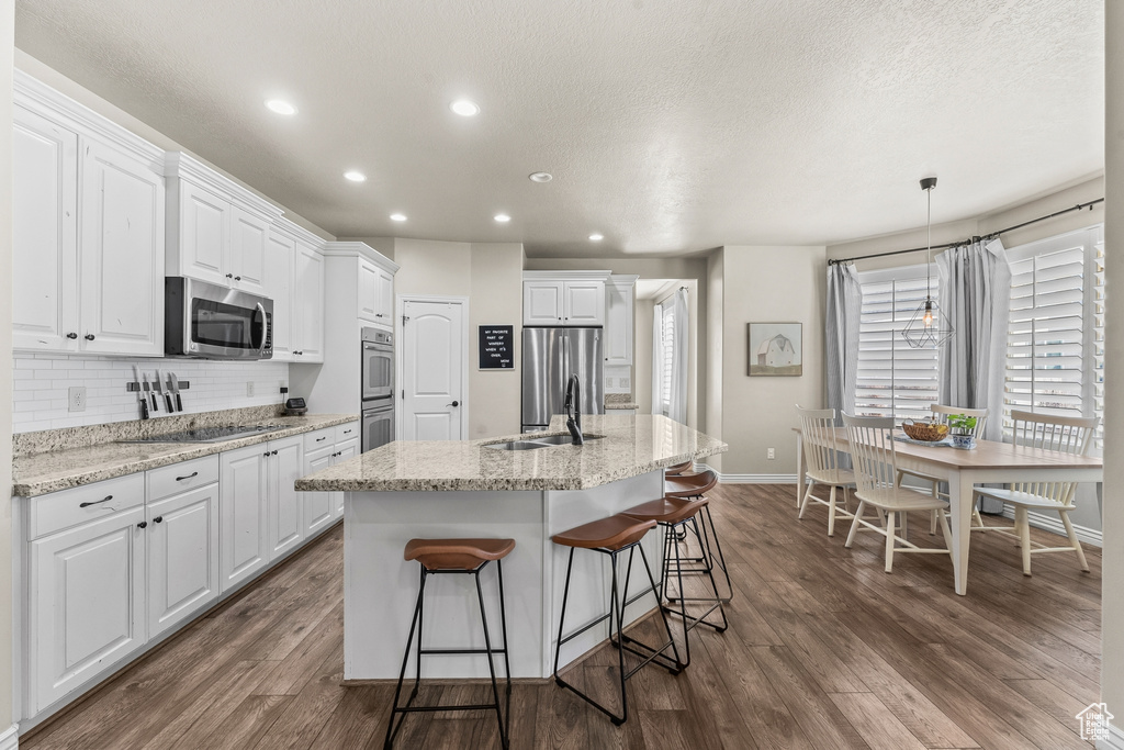 Kitchen featuring appliances with stainless steel finishes, white cabinetry, a kitchen island with sink, dark hardwood / wood-style floors, and sink