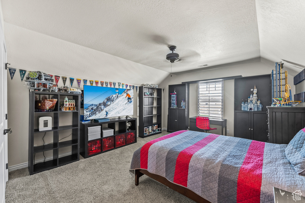Bedroom featuring carpet flooring, lofted ceiling, a textured ceiling, and ceiling fan