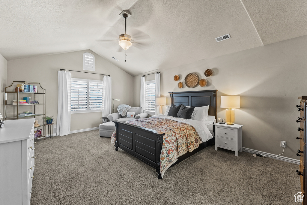 Bedroom with vaulted ceiling, a textured ceiling, ceiling fan, and dark carpet