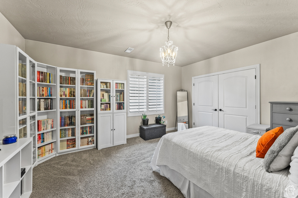 Carpeted bedroom featuring a closet and an inviting chandelier