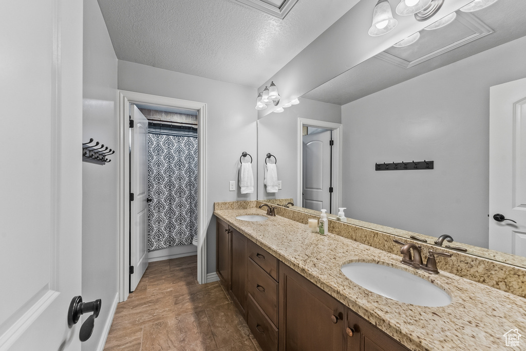 Bathroom with tile flooring, dual vanity, and a textured ceiling