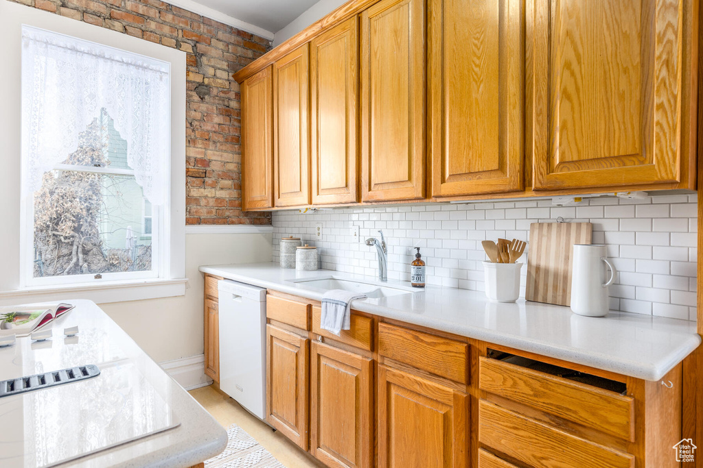 Kitchen with brick wall, tasteful backsplash, dishwasher, and sink