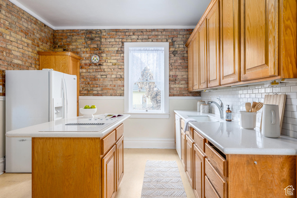Kitchen featuring a kitchen island, brick wall, sink, and tasteful backsplash