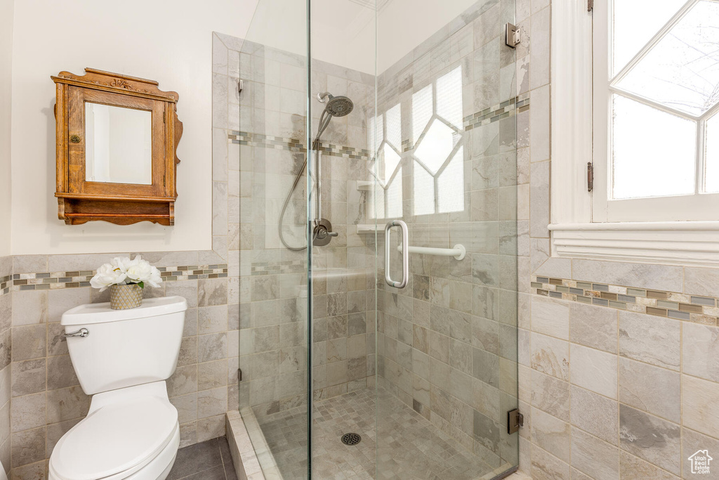 Bathroom featuring tile walls, tile floors, a shower with door, and toilet