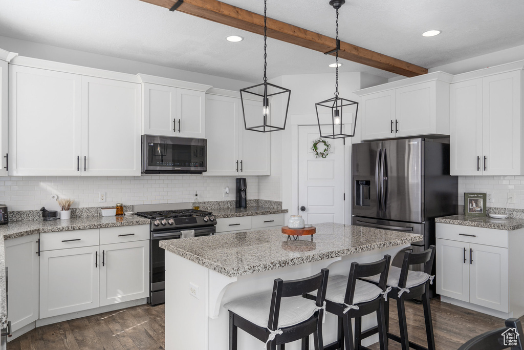 Kitchen featuring white cabinets, hanging light fixtures, stainless steel appliances, and beam ceiling
