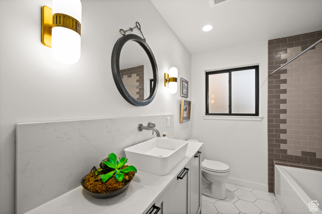 Full bathroom featuring oversized vanity, tile flooring, toilet, and tiled shower / bath