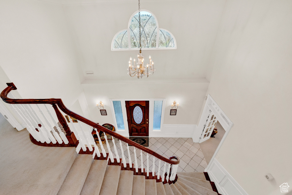 Entryway with a towering ceiling, a notable chandelier, and light tile floors