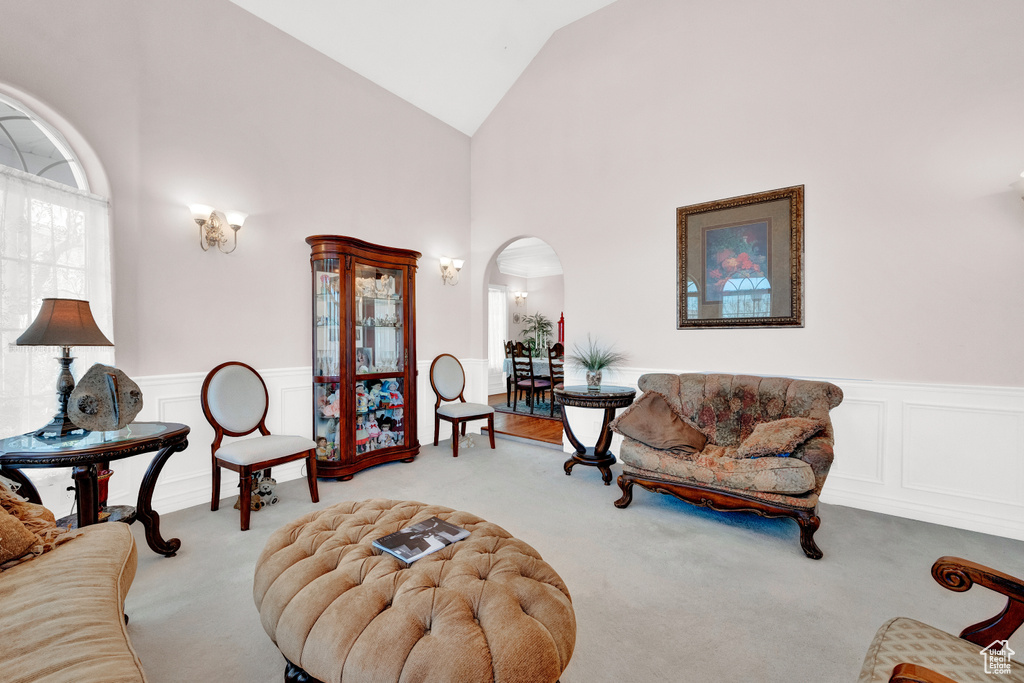 Living room with high vaulted ceiling and light carpet