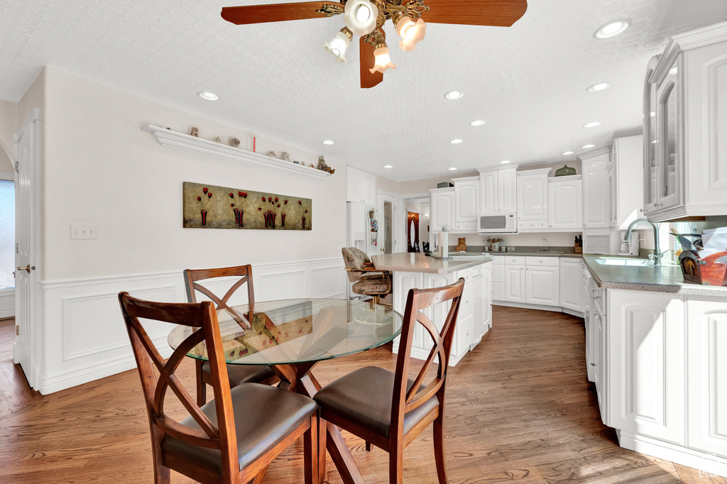 Dining space featuring ceiling fan, sink, a wealth of natural light, and dark hardwood / wood-style flooring