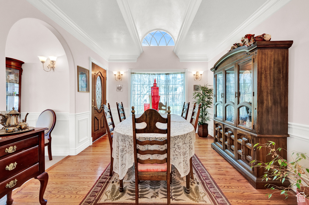 Dining space with ornamental molding and light hardwood / wood-style flooring