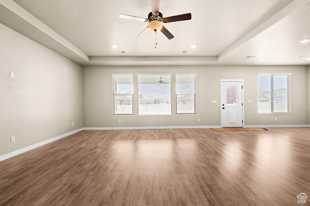 Spare room with ceiling fan, a tray ceiling, and hardwood / wood-style flooring