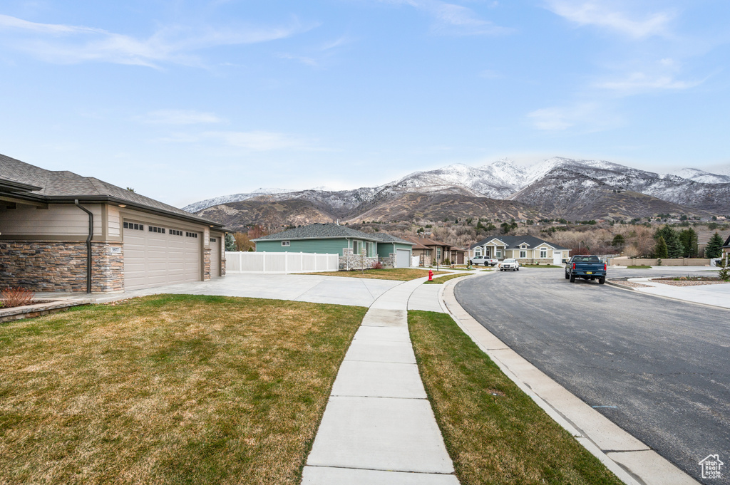 View of front of home with a front yard, a mountain view, and a garage