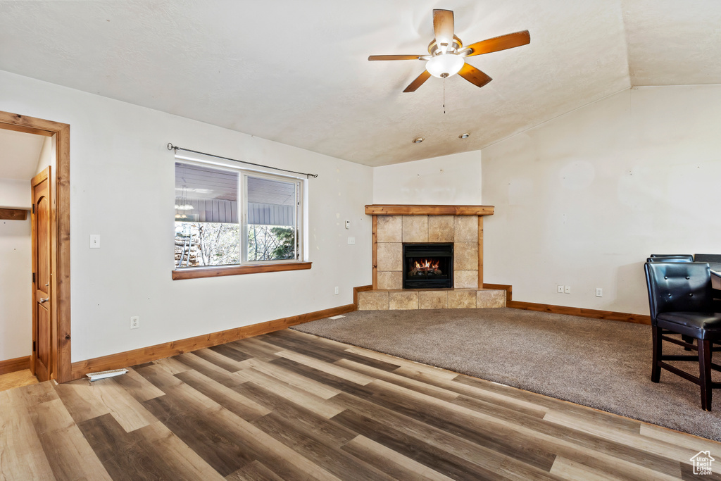 Unfurnished living room with light hardwood / wood-style flooring, a tile fireplace, ceiling fan, and vaulted ceiling