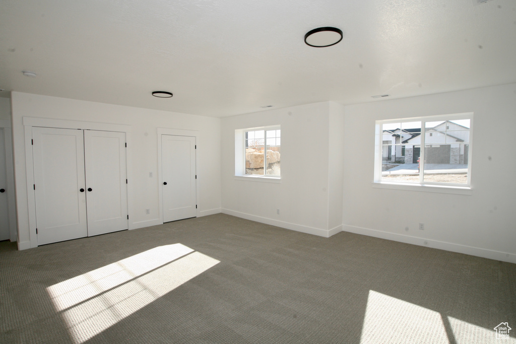 Unfurnished bedroom with light colored carpet and two closets