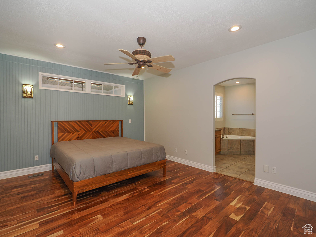Bedroom with ensuite bathroom, ceiling fan, and dark hardwood / wood-style flooring