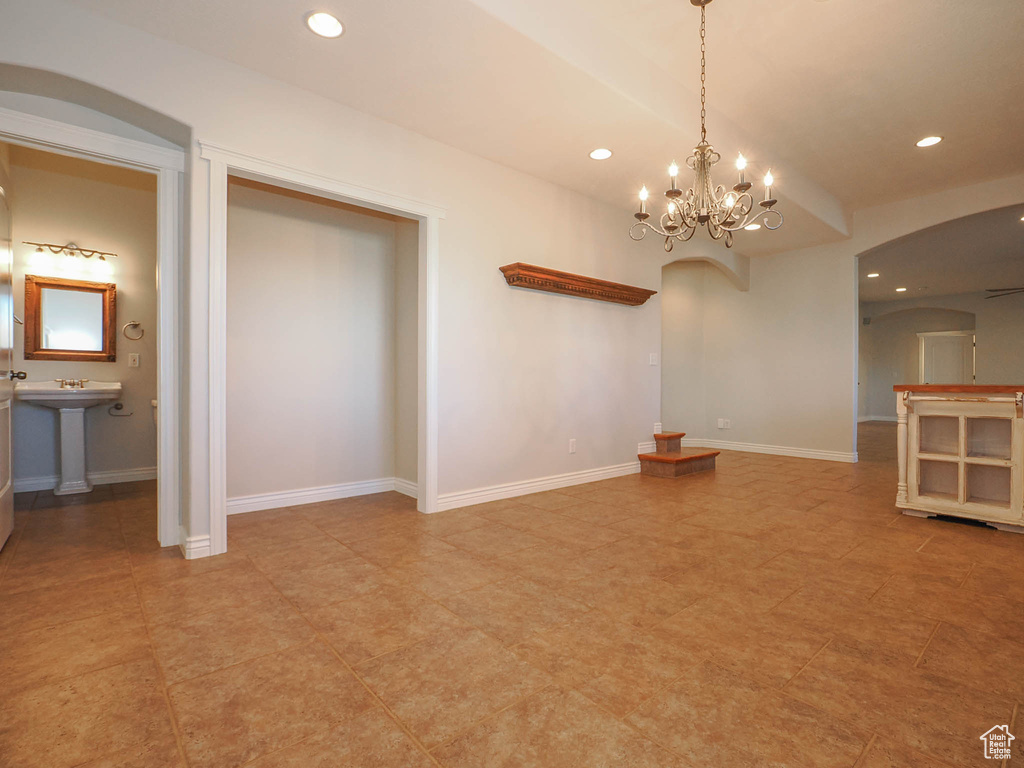 Empty room featuring light tile floors, sink, and an inviting chandelier