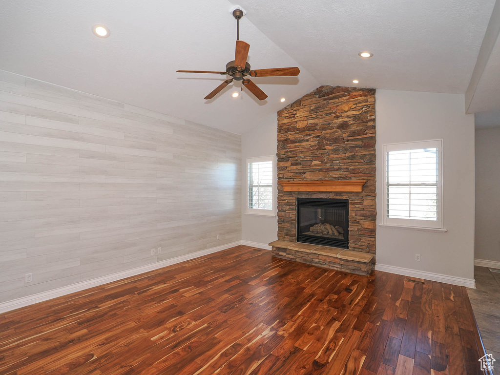 Unfurnished living room with ceiling fan, lofted ceiling, dark wood-type flooring, and a fireplace