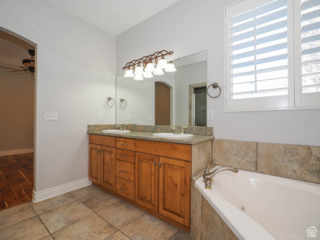 Bathroom featuring dual vanity, tile floors, ceiling fan, and tiled bath